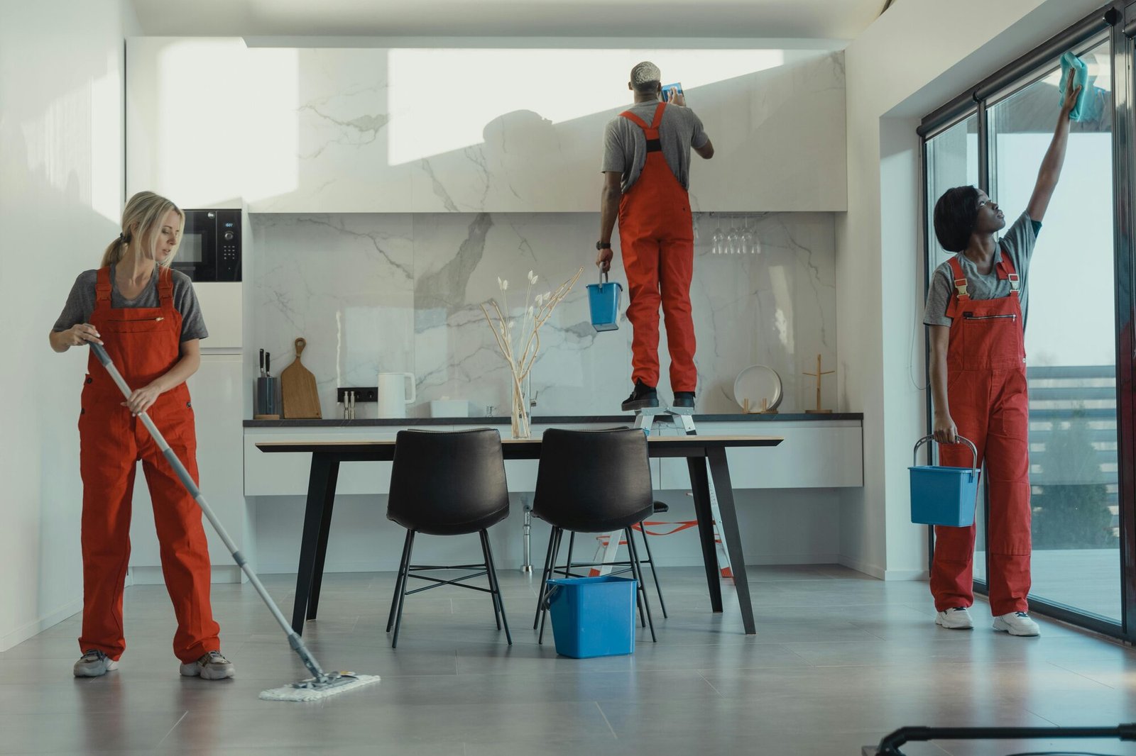 3 professional cleaners working on a kitchen